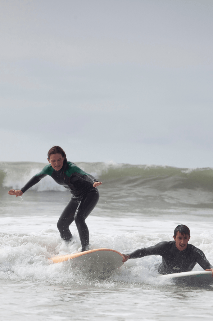 Chica coge una ola asistida por el monitor de surf.