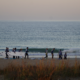 Surfcamp en El Palmar con grupo de surfistas entrenando en la orilla mientras otros esperan olas en el mar.
