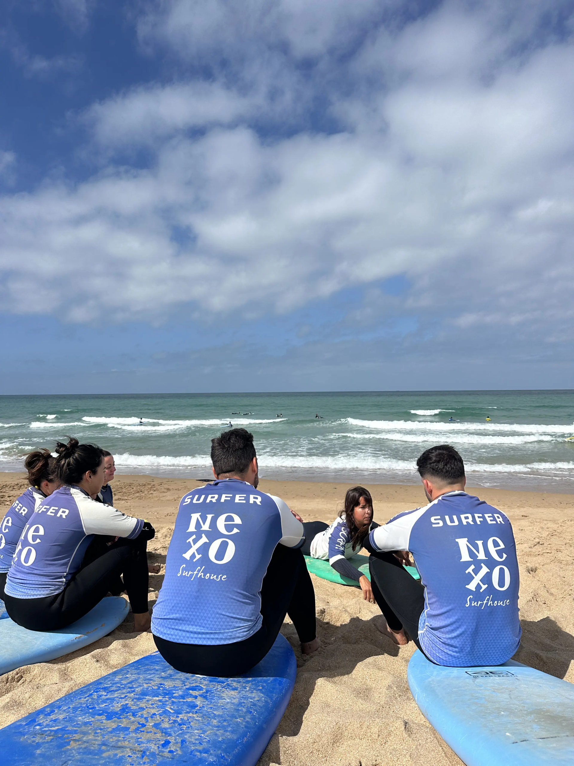 Grupo de alumnos de NEXO durante una clase de surf en El Palmar